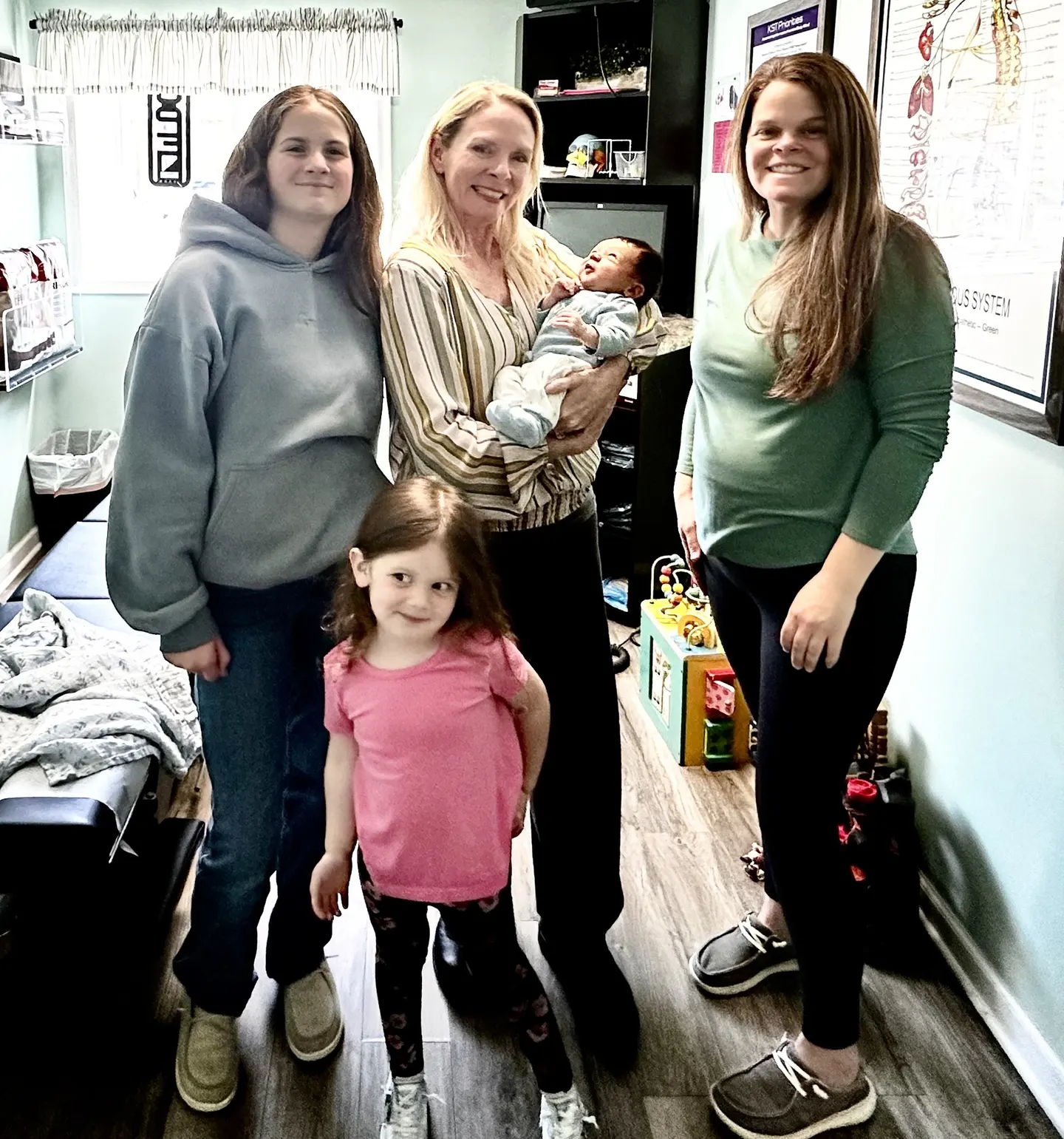 Dr. Anna Saylor with a newborn, mom and two kids in a treatment room