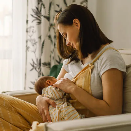 baby nursing in chair near window