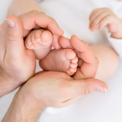 Parent hands cradling infant feet