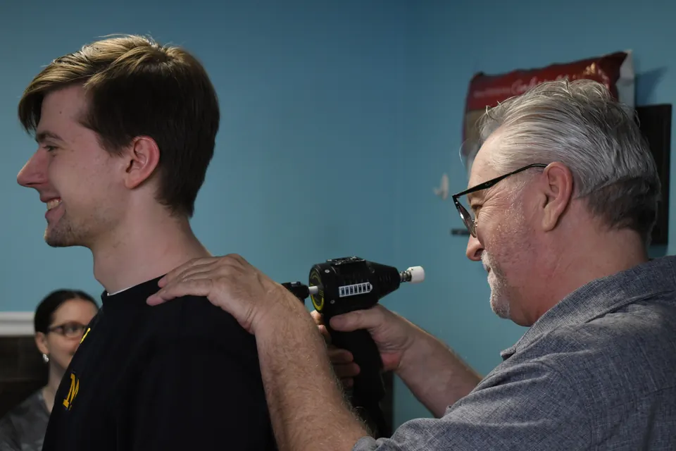 Dr. John Johr giving a smiling young patient a gentle instrument adjustment