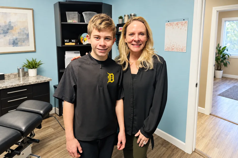 Dr. Anna Saylor smiling beside a teen patient in a Detroit baseball shirt