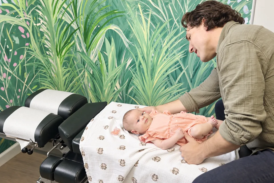 Dr. Zach Conner smiling at a newborn lying on the table in our jungle room